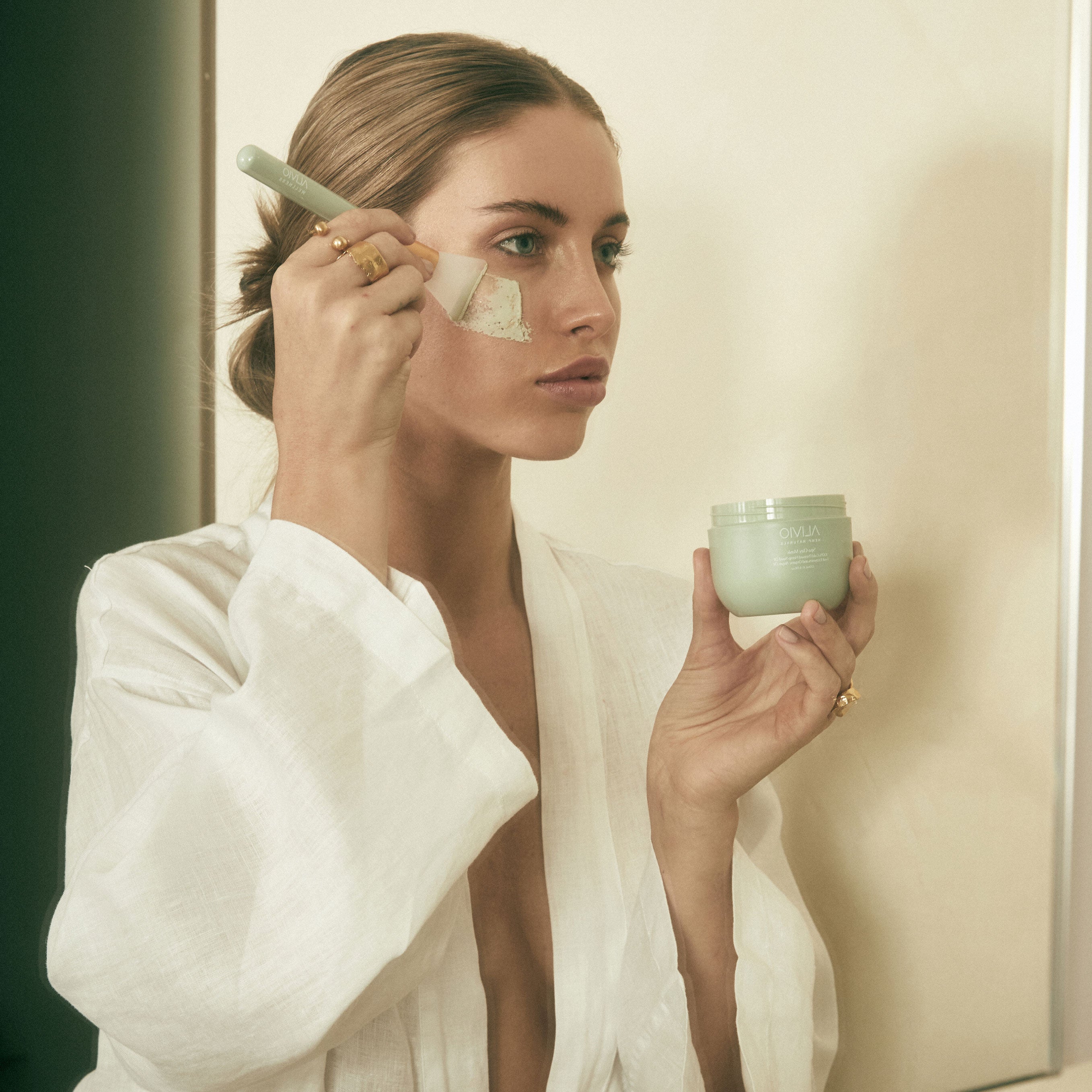 Woman applying Alivio Spa Clay Mask to face